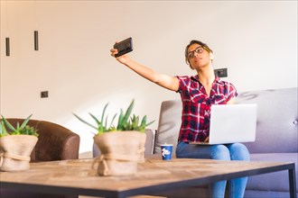 Horizontal photo with copy space of a woman taking a selfie while working at home