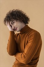 Curly haired man with brown blouse posing 6
