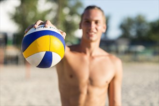 Defocused shirtless male volleyball player beach holding ball