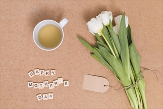 Happy mother s day text lemon tea with white tulip flowers brown backdrop