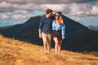 Frontal portrait of a happy couple walking along a mountain in summer
