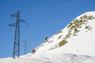 High voltage cable towers in the winter landscape with snow in the snowy mountains of the Pyrenees of Andorra