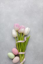 Flat lay beautiful tulips with ribbon colorful easter eggs