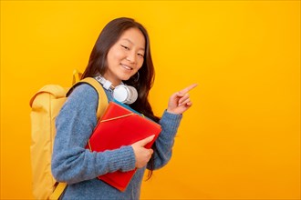 Studio photo with yellow background of a chinese student with folders
