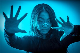 Studio photo with blue background with neon lights of a futuristic chinese woman wearing a smart goggles