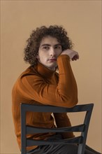 Curly haired man with brown blouse posing 11