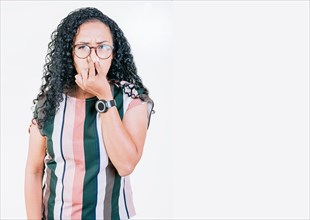 Disgusted young afro woman covering nose. Woman in glasses covering nose from a bad smell isolated. Displeased afro girl holding her nose isolated