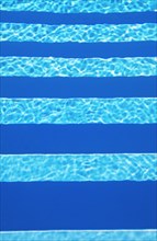 Water surface with light reflections and pool stairs in a swimming pool