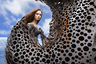 Surrealist bionic young woman embedded in liquid metal statue
