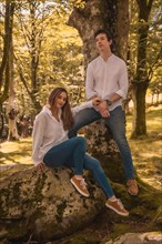 Vertical photo of a casual couple sitting together in the roots of a tree