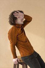 Curly haired man with brown blouse posing 2
