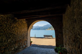 Old Beautiful Street Tunnel with Arch from Brusino Arsizio on the Waterfront in a Sunny Summer Day and with Lake Lugano and Mountain View over Morcote
