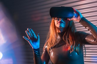 Woman submerged in metaverse reality by using VR goggles in an urban night space with neon lights