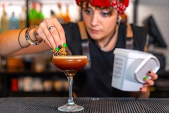 Close-up photo with focus on an accurate young bartender garnishing a cocktail glass
