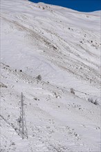 High voltage cable towers in the snowy mountains of the Pyrenees in France