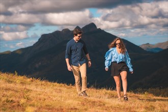 Horizontal photo with copy space of a stylish casual couple walking distracted in the mountain
