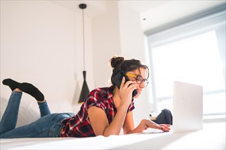 Side view of a young woman talking to the mobile while working from a hotel room