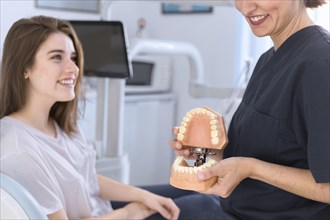 Dentist showing teeth model smiling patient