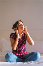Vertical portrait with copy space of a woman listening to music with eyes closed on the bed