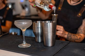 Bartender using a measuring tool to prepare a cocktail in the counter of a bar