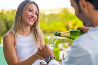 Smiling woman drinking champagne with her couple in the terrace of a luxury hotel