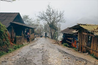 Dreamy scenery of a muddy road and native house on a foggy winter day