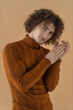 Curly haired man with brown blouse posing 10