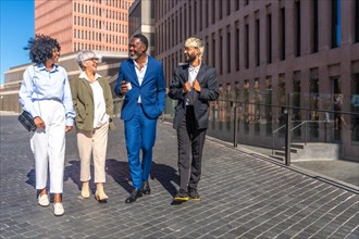 Group of multi-ethnic business people walking relaxed on a coffee break outdoors