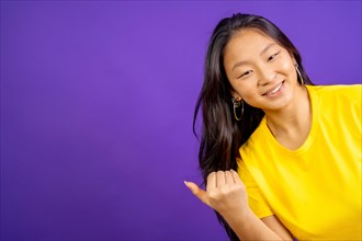 Studio photo with purple background of a chinese woman inviting to come with hand