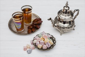Heap dry dates near cups tea turkish delights teapot