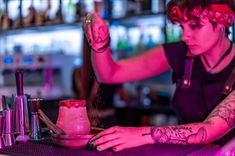 Bartender garnishing a margarita cocktail in a bar at night with neon lights