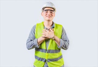 Portrait of young engineer with grateful gesture. Handsome grateful engineer with hands on chest isolated