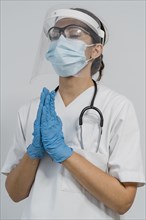 Female doctor with medical mask face shield praying