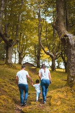 Vertical photo of the rear view of a family trekking in the forest