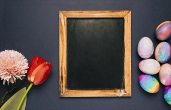 Blank blackboard with red tulip chrysanthemum easter eggs black background