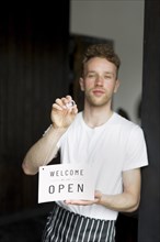Male waiter holding welcome sign