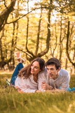 Vertical photo of lovers lying together in a park with trees