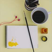 Brush notebook near coffee earphones