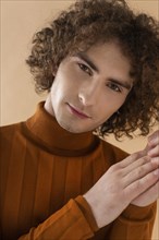 Curly haired man with brown blouse posing 8