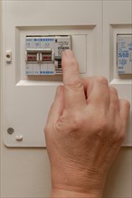 Woman pushing lever on fuse box to save energy