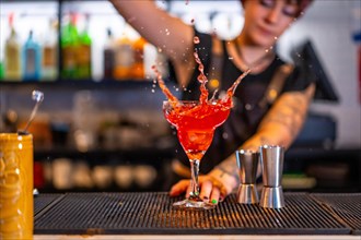 Motion photo of a bartender pouring and splashing cocktail in a glass