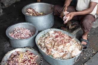 A man cleans chicken carcasses and sorts the parts for sale