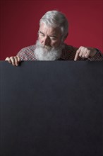 Close up senior man with grey beard pointing her finger blank black placard