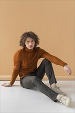 Curly haired man with brown blouse posing 13