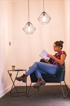 Vertical photo of a woman reading a book in a cozy space at home