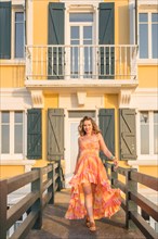 Vertical photo of a beauty model walking with a colorful long dress outdoors during sunset