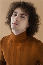 Curly haired man with brown blouse posing 4