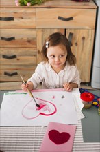Little girl painting heart paper