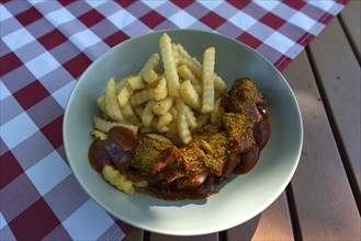 Currywurst with French fries served in a garden restaurant
