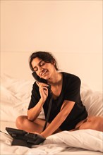 Vertical photo of a young woman using the telephone of a luxury hotel room